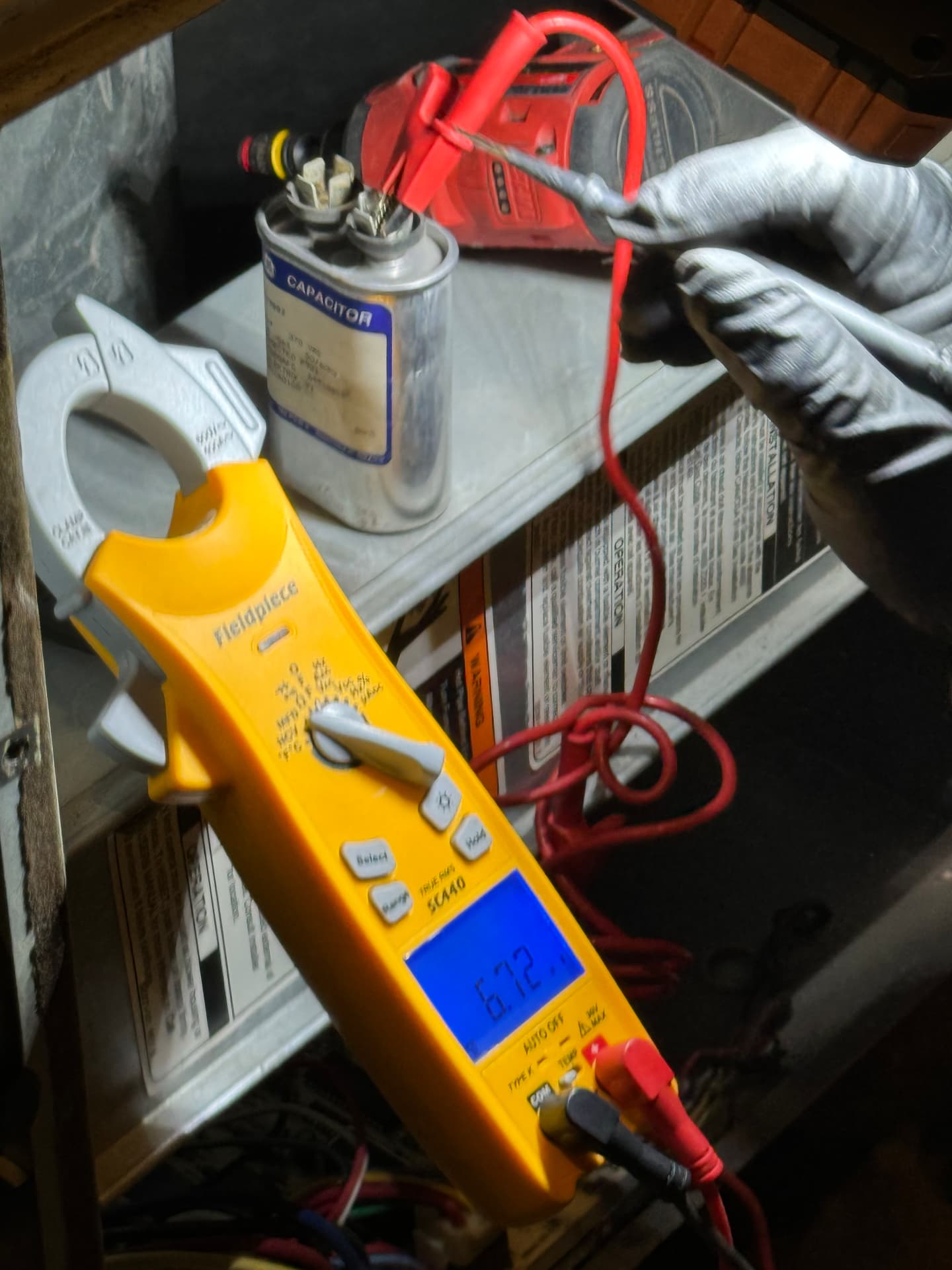 Technician testing a run capacitor with a Fieldpiece clamp meter