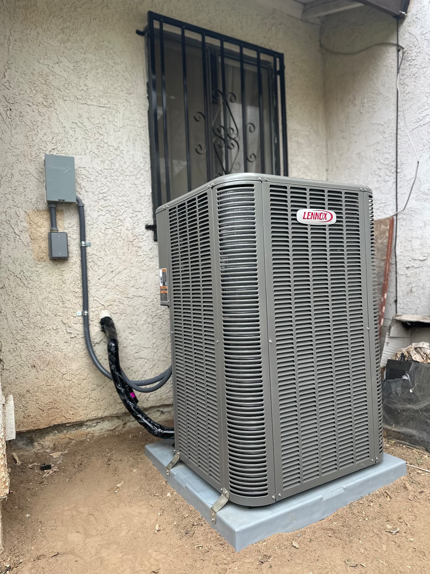Lennox condenser mounted on a new pad with insulated lineset routed to the wall