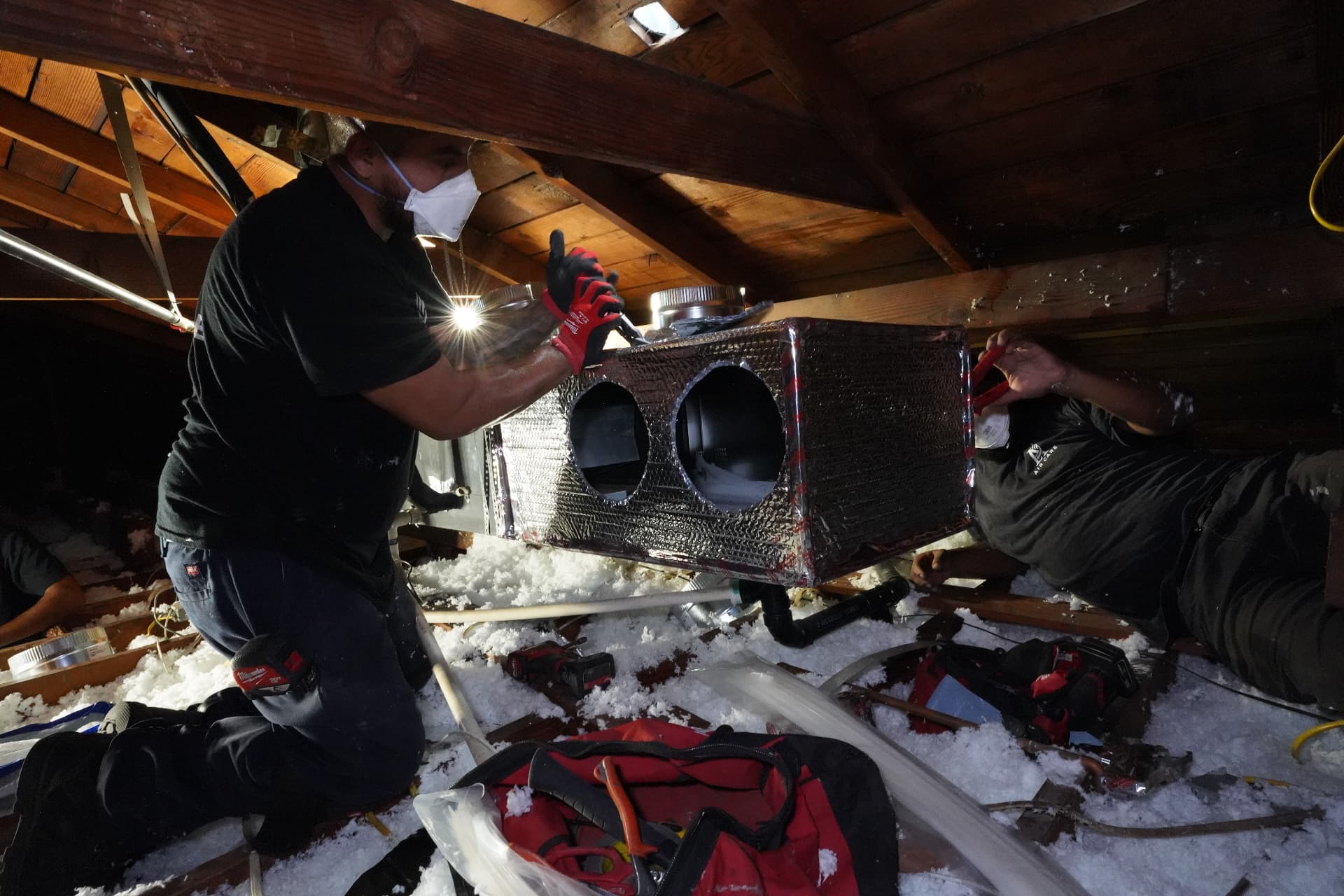 Technician sealing duct connections on a new attic plenum
