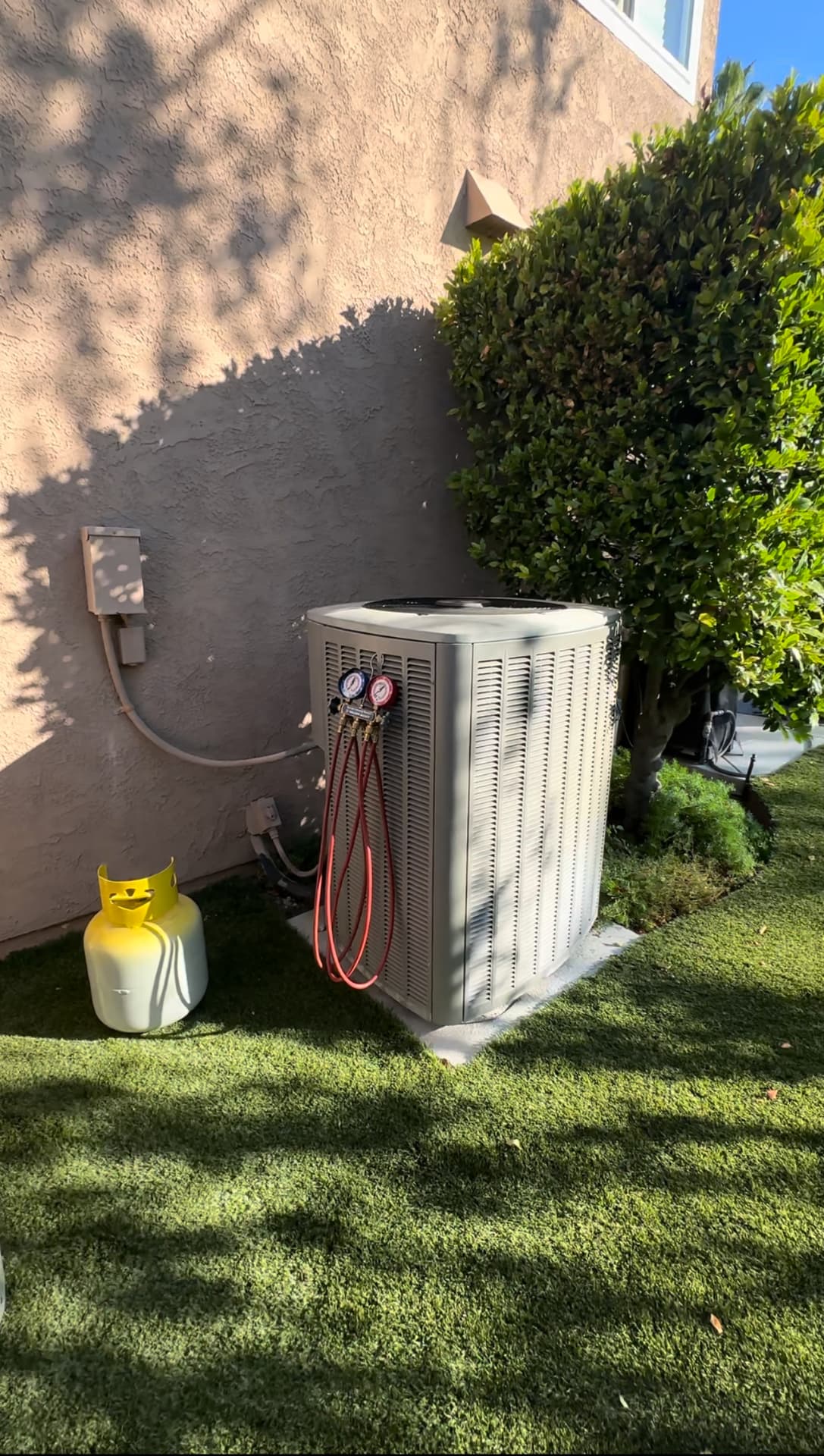 Manifold gauges connected to an outdoor AC unit during a refrigerant charge