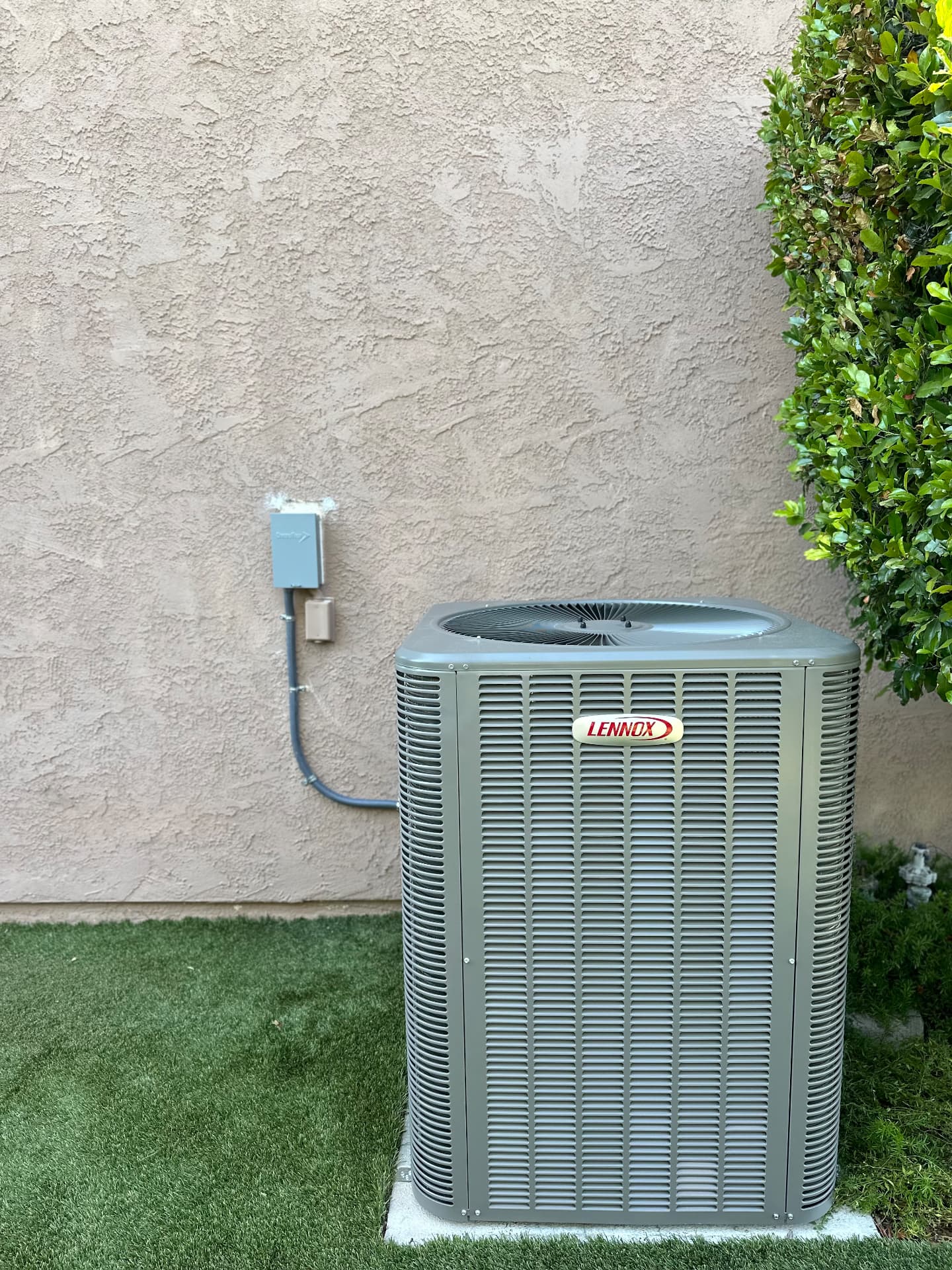New Lennox condenser installed on a concrete pad beside turf landscaping